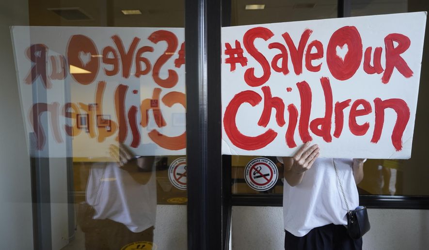 An anti-vaccine mandate protester holds a sign outside the front windows of the Los Angeles Unified School District headquarters in Los Angeles, Sept. 9, 2021 in this file photo. (AP Photo/Damian Dovarganes, File)  **FILE**