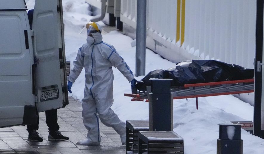 Medical workers carry a body to a van outside a COVID-19 hospital in Kommunarka, outside Moscow, Russia, Thursday, Jan. 27, 2022. Russia's state coronavirus task force has reported more than 11.3 million confirmed cases and over 328 thousands deaths, by far the largest death toll in Europe. (AP Photo/Pavel Golovkin)