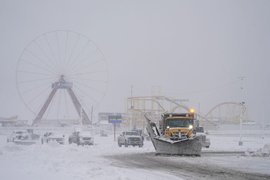 A plow cleans snow off the parking lot near amusement rides along the boardwalk during a snowstorm, Saturday, Jan. 29, 2022, in Ocean City, Md. (AP Photo/Julio Cortez)