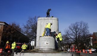 Workers remove the pedestal of the Matthew Fontaine Maury Monument on Monument Ave. in Richmond, Va., on Tuesday, Feb. 1, 2022. (Daniel Sangjib Min/Richmond Times-Dispatch via AP)
