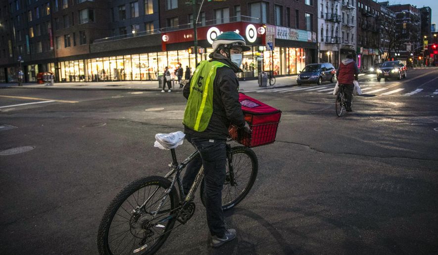 A cyclist delivering food stops at an intersection in the East Village neighborhood of New York, on Thursday, March 26, 2020. (AP Photo/Wong Maye-E, File)