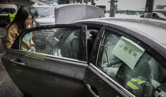 A passenger enters an Uber at LaGuardia Airport in New York on March 15, 2017. App workers like Uber drivers and food delivery workers in New York City are pressing for protections including better wages, health care and the right to unionize. (AP Photo/Seth Wenig) **FILE**