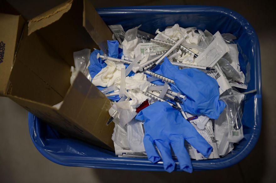 A wastebasket sits full of syringes and gloves after residents received a dose of the third Pfizer COVID-19 vaccine, at San Jeronimo nursing home, in Estella, around 38 kms from Pamplona, northern Spain, Thursday, Sept. 23. 2021. The World Health Organization says overuse of gloves, “moon suits” and the use of billions of masks and vaccination syringes to help prevent the spread of the coronavirus have spurred a huge glut of health care waste worldwide.   (AP Photo/Alvaro Barrientos)