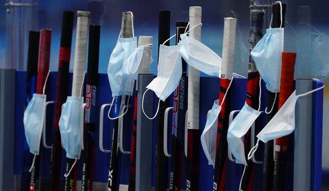 Masks hang on sticks during a practice session for Switzerland&#x27;s women&#x27;s hockey team at the 2022 Winter Olympics, Wednesday, Feb. 2, 2022, in Beijing. (AP Photo/Matt Slocum)
