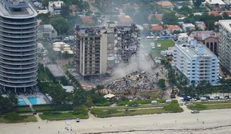 Rescue personnel work in the rubble at the Champlain Towers South Condo, Friday, June 25, 2021, in Surfside, Fla.  Seven months after an oceanfront condominium collapsed and killed 98 people near Miami, temporary structural supports have been added to areas in the underground garage of its sister tower. The Champlain Towers North condo board said in a Jan. 19, 2022, letter to unit owners that the shorting was done “in an abundance of caution” as part of an ongoing inspection by a structural engineer.(AP Photo/Gerald Herbert, File)