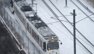 A Regional Transportation District light rail train moves down the tracks in a light snow Tuesday, Feb. 1, 2022, in Denver. Forecasters predict that a winter storm packing high winds and heavy snow will bring up to a foot of snow in some spots before moving on to the eastern plains Wednesday. (AP Photo/David Zalubowski)