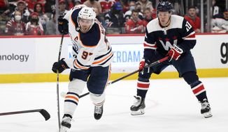 Edmonton Oilers center Connor McDavid (97) shoots the puck next to Washington Capitals right wing Daniel Sprong (10) during the second period of an NHL hockey game, Wednesday, Feb. 2, 2022, in Washington. (AP Photo/Nick Wass)