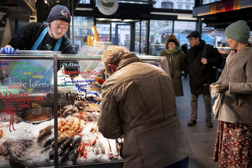 FILE - Customers at the fish market in Torvehallerne in Copenhagen, Denmark, Tuesday, Feb. 1, 2022. Starting Tuesday, it is no longer mandatory to wear protection mask anywhere in public in Denmark. The Danish Government decided that COVID-19 is no longer categorized as a socially critical disease after 31 January 2022, and has lifted COVID restrictions. Bit by bit, many countries that have been especially hard-hit by the coronavirus are easing their tough, and often unpopular, restrictive measures to fight COVID-19 even as the omicron variant — deemed less severe — has caused cases to skyrocket. (Liselotte Sabroe/Ritzau Scanpix via AP)
