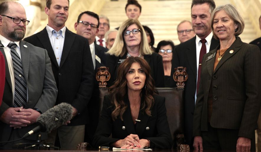 South Dakota Gov. Kristi Noem signs a bill Thursday, Feb. 3, 2022, at the state Capitol in Pierre, S.D., that will ban transgender women and girls from playing in school sports leagues that match their gender identity. (AP Photo/Stephen Groves)