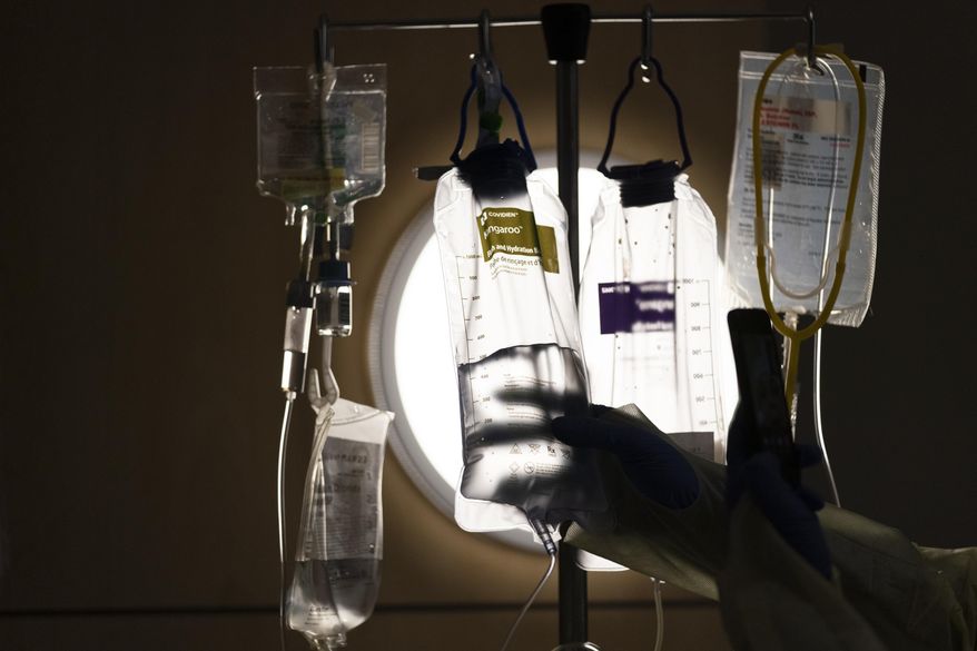 A nurse checks on IV fluids while talking to a COVID-19 patient at Providence Holy Cross Medical Center in Los Angeles, Dec. 13, 2021. (AP Photo/Jae C. Hong, File)