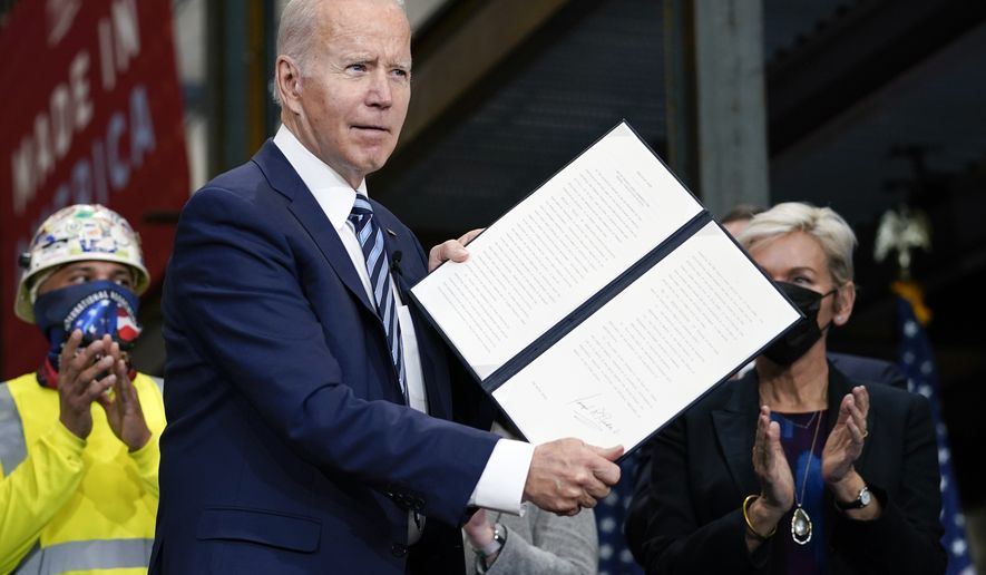 President Joe Biden holds up an executive order on project labor agreements after signing it at the Ironworkers Local 5 in Upper Marlboro, Md., Friday, Feb. 4, 2022. Energy Secretary Jennifer Granholm, right, applauds with others. (AP Photo/Carolyn Kaster)