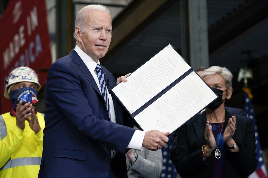 President Joe Biden holds up an executive order on project labor agreements after signing it at the Ironworkers Local 5 in Upper Marlboro, Md., Friday, Feb. 4, 2022. Energy Secretary Jennifer Granholm, right, applauds with others. (AP Photo/Carolyn Kaster)