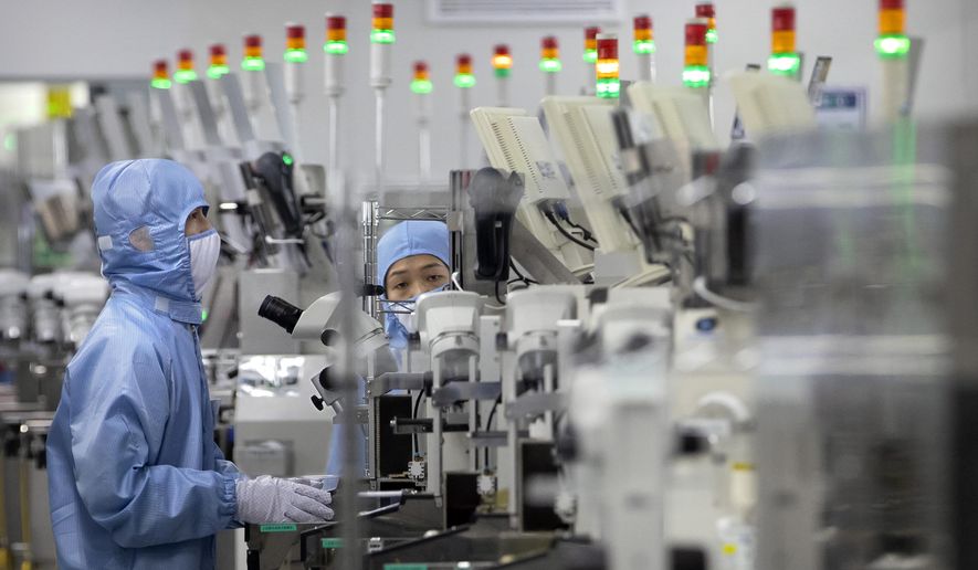 Employees wearing protective equipment work at a semiconductor production facility for Renesas Electronics during a government organized tour for journalists in Beijing, on May 14, 2020. House Democrats are poised to approve legislation Friday, Feb. 4, 2022, that they say positions the United States to better compete with China economically and on the global stage by strengthening the domestic semiconductor industry, shoring up strained supply chains and bolstering international alliances. (AP Photo/Mark Schiefelbein, File)