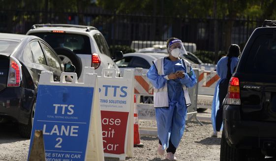 Workers wear protective equipment at a COVID-19 testing site Wednesday, Jan. 26, 2022, in the Boyle Heights section of Los Angeles. With the brutal omicron wave rapidly easing its grip, new cases of COVID-19 in the U.S. are falling in 49 of the 50 states. (AP Photo/Marcio Jose Sanchez) ** FILE **