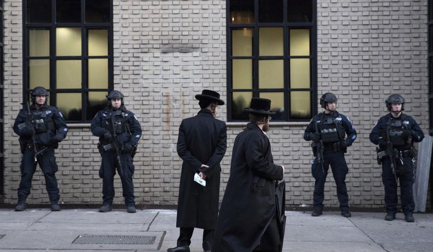 Orthodox Jewish men pass New York City police guarding a Brooklyn synagogue on Dec. 11, 2019 prior to a funeral for Mosche Deutsch, a rabbinical student from Brooklyn who was killed in a shooting at a Jersey City, N.J. market. On Wednesday, Jan. 15, 2019, a group of security experts recommended that Jewish congregations opting to deploy armed security personnel in the wake of deadly attacks on synagogues should — if possible — use uniformed law enforcement officers rather than private guards or volunteers from the community. (AP Photo/Mark Lennihan, File)