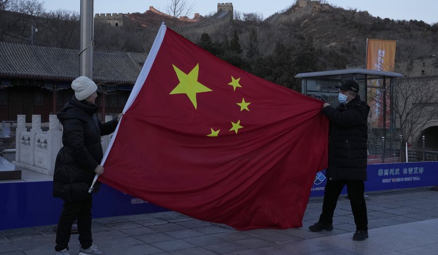 Tourists pose with a Chinese national flag as they visit the Badaling section of the Great Wall of China on the outskirts of Beijing on Tuesday, Feb. 8, 2022, in Beijing. (AP Photo/Ng Han Guan)