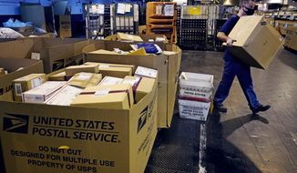 FILE - A worker carries a large parcel at the United States Postal Service sorting and processing facility Nov. 18, 2021, in Boston. Congress would lift onerous budget requirements that have helped push the Postal Service deeply into debt and would require it to continue delivering mail six days per week under bipartisan legislation that approached House approval Tuesday, Feb. 8, 2022. (AP Photo/Charles Krupa, File)