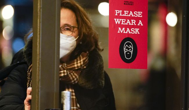 A sign asks shoppers to wear masks in New York, Wednesday, Feb. 9, 2022. New York Gov. Kathy Hochul announced Wednesday that the state will end a COVID-19 mask mandate requiring face coverings in most indoor public settings, but will keep masking rules in place in schools for now. (AP Photo/Seth Wenig)