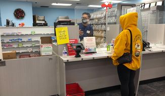 A woman waits at the pharmacy counter at a CVS on Sunset Boulevard in the Echo Park neighborhood of Los Angeles where the location is sold out of CIOVID at-home rapid test kits during the omicron surge on Tuesday, Jan. 4, 2021. (AP Photos/Stefanie Dazio)