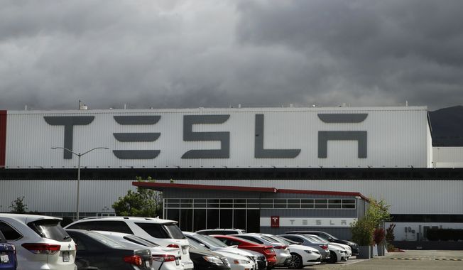 Vehicles are parked outside the Tesla plant, in Fremont, Calif., on May 12, 2020. California sued Tesla Inc. on Wednesday, Feb. 9, 2022,  over allegations of discrimination and harassment of Black employees at its San Francisco Bay area factory. (AP Photo/Ben Margot, File)