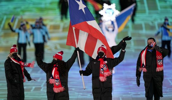 Kellie Delka and William C. Flaherty, of Puerto Rico, lead their team in during the opening ceremony of the 2022 Winter Olympics, Friday, Feb. 4, 2022, in Beijing. (AP Photo/David J. Phillip)