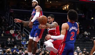 Washington Wizards forward Kyle Kuzma (33) is defended by Detroit Pistons forward Saddiq Bey (41) and guard Cade Cunningham (2) during the first half of an NBA basketball game, Monday, Feb. 14, 2022, in Washington. (AP Photo/Evan Vucci)