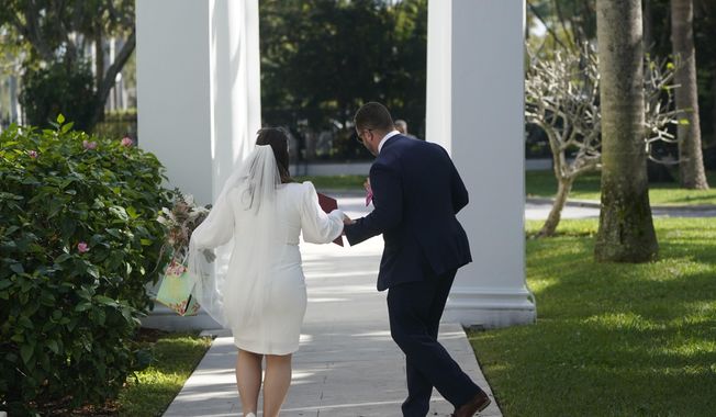 Danielle Green, left, and her new husband Yehonatan Miron dance as they leave after being married during a Valentine&#x27;s Day group wedding ceremony, Monday, Feb. 14, 2022, outside the Flagler Museum in Palm Beach, Fla. The pair were one of nine couples married by the Clerk of the Circuit Court &amp;amp; Comptroller for Palm Beach County during the annual event. (AP Photo/Wilfredo Lee)