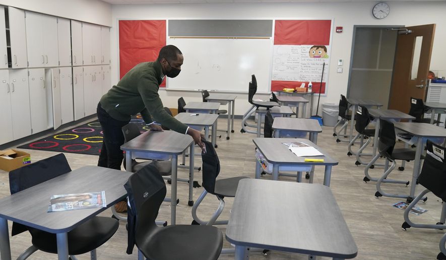 Isaac Adjei aligns desk in his classroom at Pleasant Run Elementary School, Tuesday, Feb. 8, 2022, in Indianapolis. A contentious Indiana bill that Republican lawmakers say would increase transparency of school curricula could undergo significant changes Wednesday, Feb. 16 in response to mounting criticism from teachers and education advocates. (AP Photo/Darron Cummings)