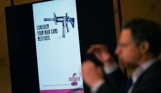 An image of the advertising used for an AR-15-style rifle is displayed while attorney Josh Koskoff speaks during a news conference in Trumbull, Conn., Tuesday, Feb. 15, 2022. The families of nine victims of the Sandy Hook Elementary School shooting have agreed to a $73 million settlement of a lawsuit against the maker of the rifle used to kill 20 first graders and six educators in 2012, their attorney said Tuesday. (AP Photo/Seth Wenig)