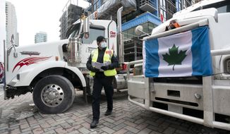 A police officer walks between parked trucks as he distributes a notice to protesters, Wednesday, Feb. 16, 2022 in Ottawa. Ottawas police chief was ousted Tuesday amid criticism of his inaction against the trucker protests that have paralyzed Canada&#39;s capital for over two weeks, while the number of blockades maintained by demonstrators at the U.S. border dropped to just one.  (Adrian Wyld /The Canadian Press via AP)