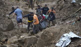 Residents and volunteers remove the body of a landslide victim in Petropolis, Brazil, Wednesday, Feb. 16, 2022. Extremely heavy rains set off mudslides and floods in a mountainous region of Rio de Janeiro state, killing multiple people, authorities reported. (AP Photo/Silvia Izquierdo)