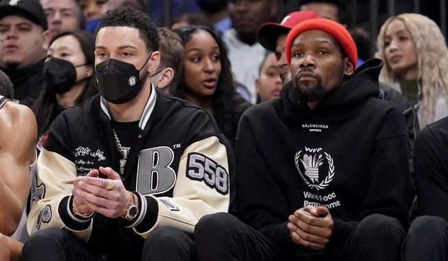 Brooklyn Nets forward Ben Simmons, left, sits with forward Kevin Durant, right, on the bench during the first half of an NBA basketball game against the New York Knicks, Wednesday, Feb. 16, 2022, in New York. (AP Photo/John Minchillo) **FILE**