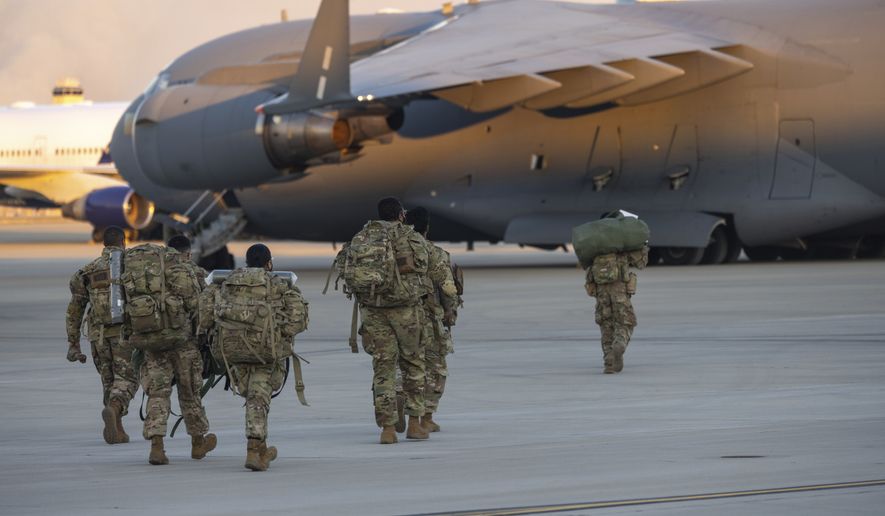 Members of the 82nd Airborne Division of the U.S. Army walk on the tarmac at Pope Field ahead of deployment to Poland from Fort Bragg, N.C. on Monday, Feb. 14, 2022. They are among soldiers the Department of Defense is sending in a demonstration of American commitment to NATO allies worried at the prospect of Russia invading Ukraine.  (AP Photo/Nathan Posner)