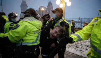 A man is arrested by police as protesters and supporters gather as a protest against COVID-19 measures that has grown into a broader anti-government protest continues to occupy downtown Ottawa, Ontario, on Thursday, Feb. 17, 2022. (Cole Burston/The Canadian Press via AP)