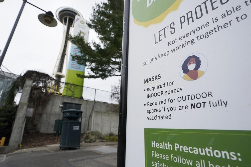 A sign near the Space Needle notes that masks are required for indoor spaces, Thursday, Feb. 17, 2022, in Seattle. Gov. Jay Inslee said Thursday that the statewide indoor mask mandate in Washington state will lift on March 21, 2022, including at schools and child care facilities. (AP Photo/Ted S. Warren)