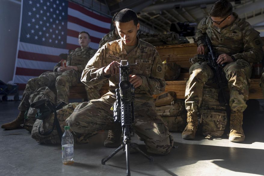 Members of the 82nd Airborne Division of the U.S. Army clean weaponry ahead of deployment to Poland from Fort Bragg, N.C. on Monday, Feb. 14, 2022. They are among soldiers the Department of Defense is sending in a demonstration of American commitment to NATO allies worried at the prospect of Russia invading Ukraine. (AP Photo/Nathan Posner)