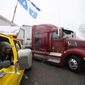 A person in a pickup truck and trailer blocking Wellington Street watches as a semi-trailer truck drives away, during an ongoing protest against COVID-19 measures that has grown into a broader anti-government protest, in Ottawa, Ontario, on Thursday, Feb. 17, 2022. (Justin Tang/The Canadian Press via AP)