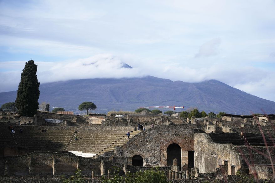 The Mt. Vesuvius volcano towers over the remains of the ancient town of Pompeii in southern Italy, Tuesday, Feb. 15, 2022. In a few horrible hours, Pompeii went from being a vibrant city to a dead one, smothered by a furious volcanic eruption in 79 AD. Then in this century, Pompeii appeared alarmingly on the precipice of a second death, assailed by decades of neglect, mismanagement and scanty systematic maintenance of heavily visited ruins. (AP Photo/Gregorio Borgia)