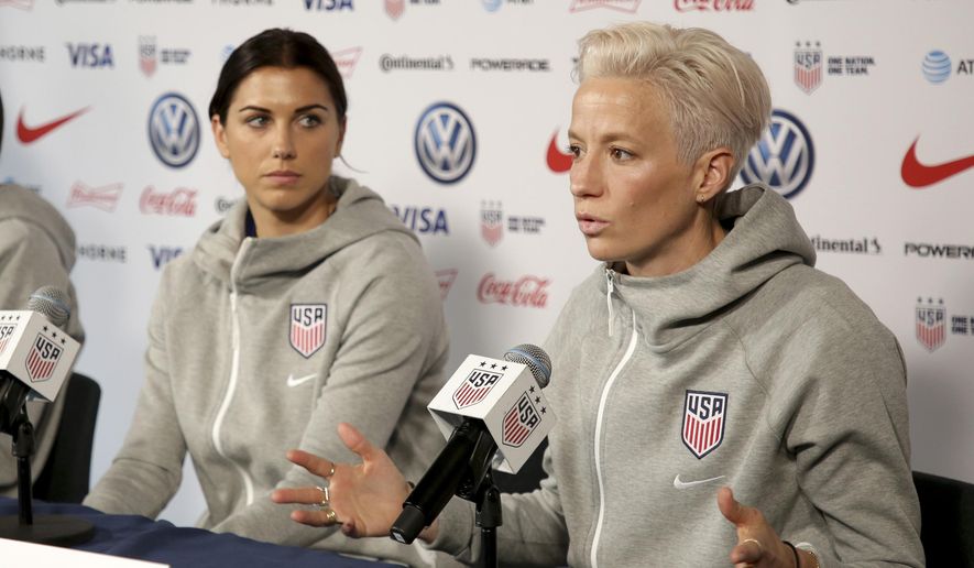 United States women&#39;s national soccer team members Alex Morgan, left, listens as teammate Megan Rapinoe speak to reporters during a news conference in New York, Friday, May 24, 2019. U.S. women soccer players reached a landmark agreement with the sport’s American governing body to end a six-year legal battle over equal pay, a deal in which they are promised $24 million plus bonuses that match those of the men. The U.S. Soccer Federation and the women announced a deal Tuesday, Feb. 22, 2022, that will have players split $22 million, about one-third of what they had sought in damages. (AP Photo/Seth Wenig, File) **FILE**