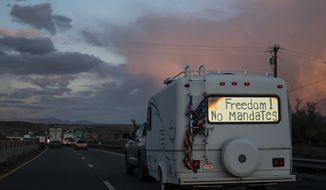 A trailer with the words &quot;Freedom! No Mandate&quot; on its back window travels with a trucker caravan heading toward Washington D.C. to protest COVID-19 mandates on Wednesday, Feb. 23, 2022, near Needles, Calif. (AP Photo/Nathan Howard)