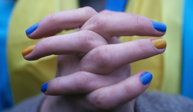 A woman, her fingernails painted in the colors of the Ukrainian national flag, takes part in a protest against the escalation of the tension between Russia and Ukraine, near the Russian Embassy in Berlin, Germany, Tuesday, Feb. 22, 2022. Europe braced for further confrontation Wednesday, Feb. 23, 2022, after tensions over Ukraine escalated dramatically when Russian President Vladimir Putin got the OK to use military force outside his country and the West responded with sanctions. (AP Photo/Markus Schreiber)