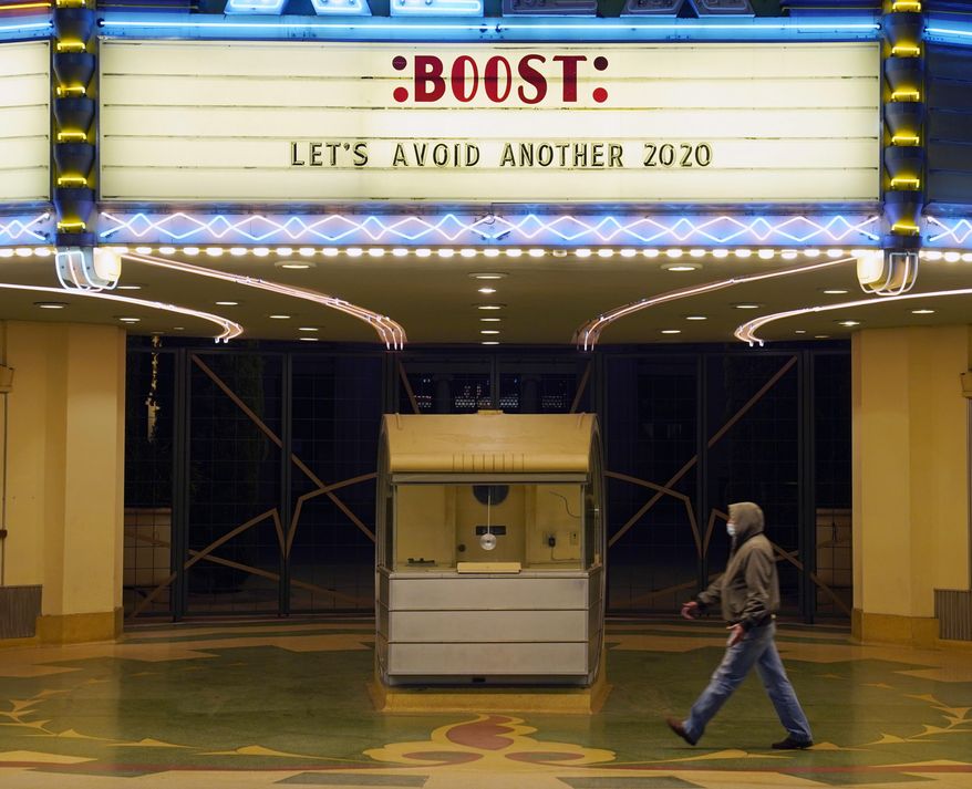 A man walks underneath the marquee of the Alex Theatre in Glendale, Calif., which bears a message urging people to get COVID-19 vaccine booster shots, Monday, Jan. 24, 2022. The vaccination drive against COVID-19 in the U.S. is grinding to a halt, and lagging demand is especially stark in conservative corners of the country where many people weren't interested in the shots in the first place. (AP Photo/Chris Pizzello) **FILE**