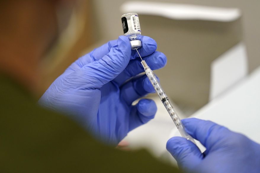 A health care worker fills a syringe with the Pfizer COVID-19 vaccine at Jackson Memorial Hospital, Oct. 5, 2021, in Miami. A dozen U.S. Air Force officers have filed a lawsuit against the federal government after the military denied their religious exemptions to the mandatory COVID-19 vaccine. (AP Photo/Lynne Sladky, File)