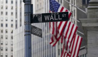 The Wall Street street sign is framed by the American flags flying outside the New York Stock exchange, Friday, Jan. 14, 2022, in the Financial District, in this file photo.   (AP Photo/Mary Altaffer, File)  **FILE**
