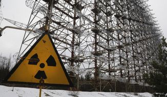 A Soviet-era top secret object Duga, an over-the-horizon radar system once used as part of the Soviet missile defense early-warning radar network, seen behind a radioactivity sign in Chernobyl, Ukraine, on Nov. 22, 2018. (AP Photo/Efrem Lukatsky, File)