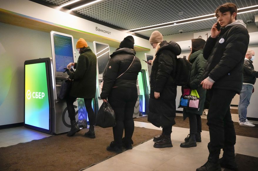 People stand in line to withdraw money from an ATM in Sberbank in St. Petersburg, Russia, Friday, Feb. 25, 2022. Russians flocked to banks and ATMs on Thursday and Friday shortly after Russia launched an attack on Ukraine and the West announced crippling sanctions. According to Russia's Central Bank, on Thursday alone Russians have withdrawn 111 billion rubles (about $1.3 billion) in cash. (AP Photo/Dmitri Lovetsky)