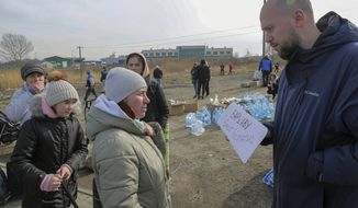 A Polish volunteer, right, offers Ukrainian refugees transportation to Warsaw, at the Medyka border crossing, in Medyka, Poland, Saturday, Feb. 26, 2022. The U.N. refugee agency says nearly 120,000 people have so far fled Ukraine into neighboring countries in the wake of the Russian invasion. (AP Photo/Visar Kryeziu)