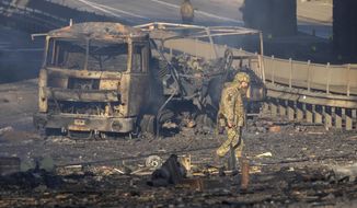 A Ukrainian soldier walks past debris of a burning military truck, on a street in Kyiv, Ukraine, Saturday, Feb. 26, 2022. Russian troops stormed toward Ukraine&#39;s capital Saturday, and street fighting broke out as city officials urged residents to take shelter. (AP Photo/Efrem Lukatsky)