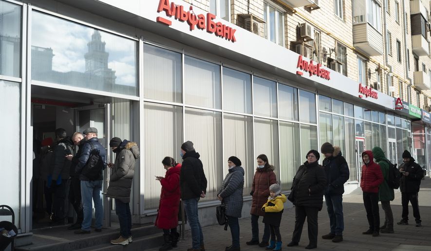 People stand in line to withdraw money from an ATM of Alfa Bank in Moscow, Russia, Sunday, Feb. 27, 2022. Russians flocked to banks and ATMs shortly after Russia launched an attack on Ukraine and the West announced crippling sanctions. (AP Photo/Victor Berzkin)