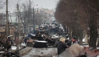 People look at the gutted remains of Russian military vehicles on a road in the town of Bucha, close to the capital Kyiv, Ukraine, Tuesday, March 1, 2022. Russia on Tuesday stepped up shelling of Kharkiv, Ukraine&#39;s second-largest city, pounding civilian targets there. Casualties mounted and reports emerged that more than 70 Ukrainian soldiers were killed after Russian artillery recently hit a military base in Okhtyrka, a city between Kharkiv and Kyiv, the capital. (AP Photo/Serhii Nuzhnenko)